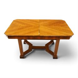 Art Deco walnut extending dining table, book-matched veneered shaped top, raised on cluster-column supports, united by stretchers, additional leaf extends to 185cm  