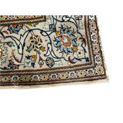 Persian Kashan ivory ground carpet, the field decorated with scrolling branches with foliate and palmette motifs, repeating border with stylised plant motifs, within floral and geometric pattern guard stripes 