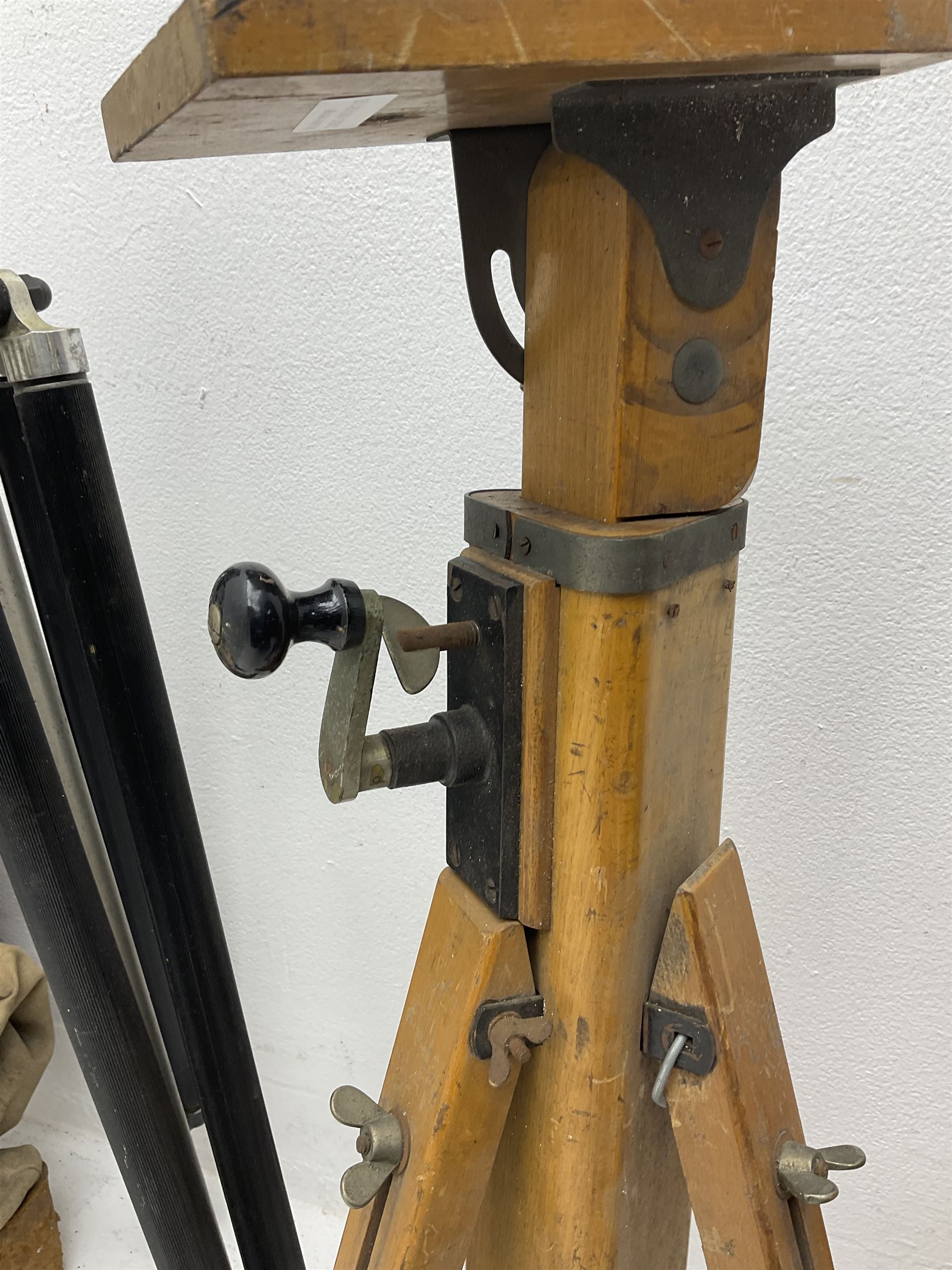 Three wooden adjustable tripods for plate cameras, together with a Linhof of Munchen metal tripod in a canvas case 