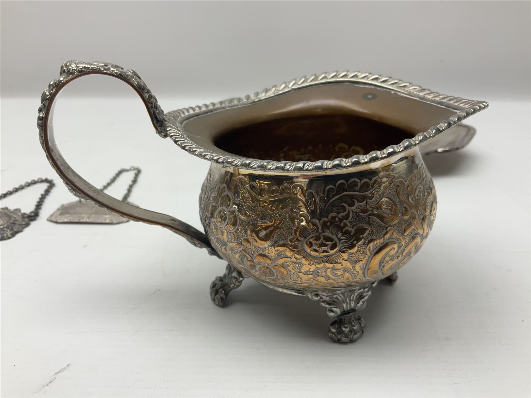 Silver plated tray, with shaped rim and embossed with a dog and crown to centre, stamped Valenti, together with three silver plated decanter labels, two port and one Bucellas, a plated cream jug with embossed floral decoration and a pair of plated fish knives engraved with double headed eagle to handle, tray W25.5