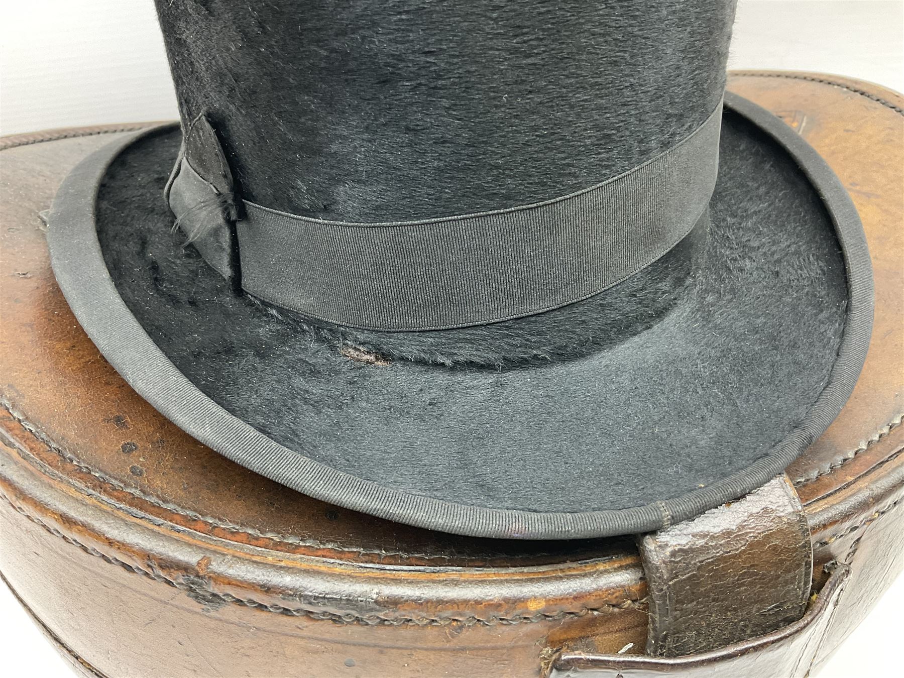 Early 20th century black silk top hat by Woodrow of Manchester and London, with manufacturer's stamp to the silk lined interior, housed in fitted tan leather hat box with removable internal compartments with straps, brass escutcheon and engraved plaque, hat internal measurements approx 20cm x 15cm