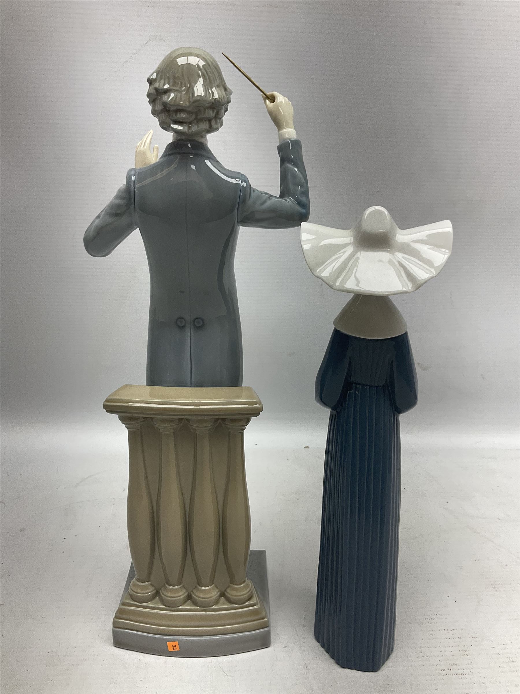 Two Lladro figures, comprising Conductor no 5196 and Prayerful Moment no 5500 together with a Lladro plaque and two Lladro candle holders, Dolphins at Play no 17666 and Sailing the Seas no 17665, all with original boxes, largest example H33cm 