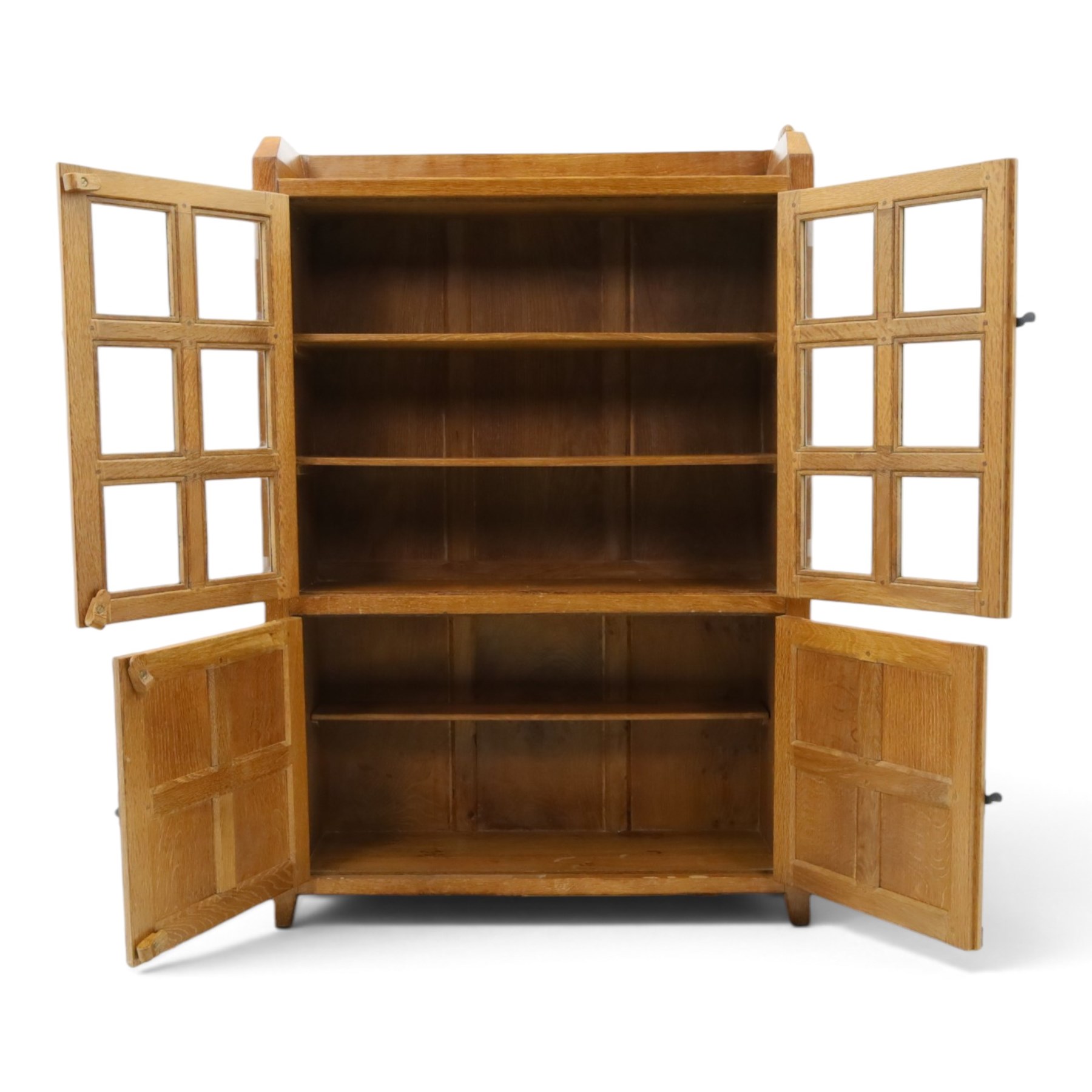 Rabbitman - oak glazed bookcase or display cabinet, lightly adzed rectangular top with raised gallery, twin glazed doors enclosing two shelves, over a pair of panelled cabinet doors with wrought iron fittings, with carved rabbit signature, by Peter Heap of Wetwang