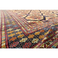 Central Asian Turkmen, main field with octagonal guls enclosing hooked diamond motifs in shades of madder gold, ivory, and indigo set against a dark ground within multiple polychrome borders of geometric devices and stepped motifs 