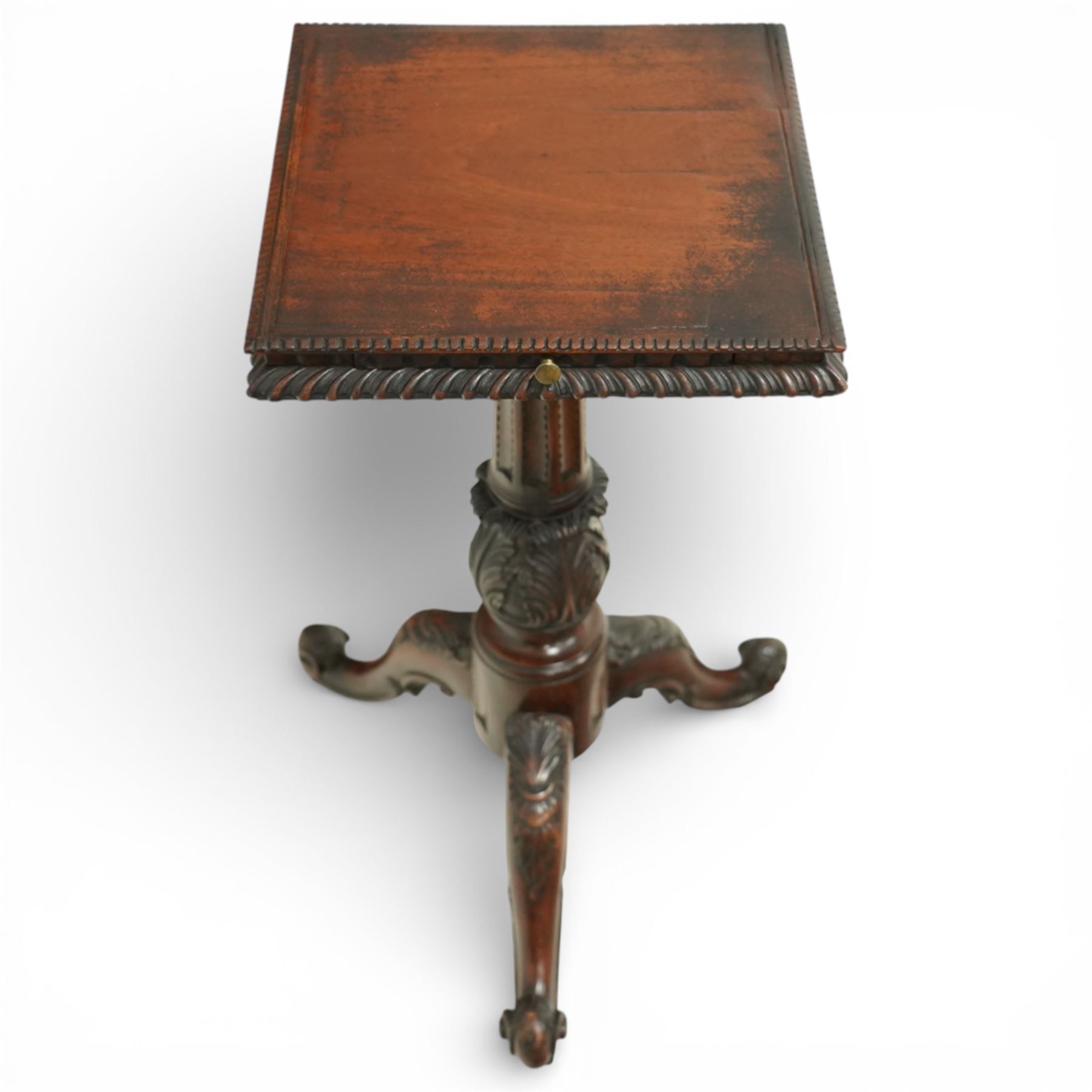 George III style carved mahogany kettle stand, the square top with gadrooned edge above a pull out slide, raised on a turned and carved baluster column issuing three carved cabriole legs terminating in scroll feet