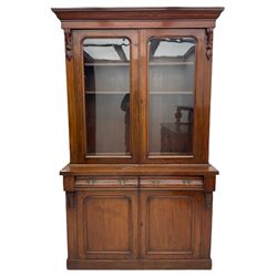 Victorian mahogany bookcase on cupboard, projecting cornice over two glazed doors and carved corbels, fitted with two drawers and double cupboard, plinth base