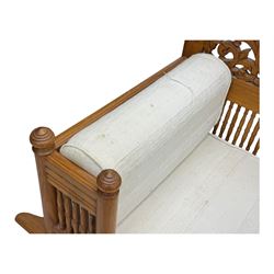 Early 20th century carved teak Howdah elephant chair, with pierced floral and foliate carved backrest, spindle gallery arm supports, cream upholstered cushions, splayed legs on a curved reeded base 