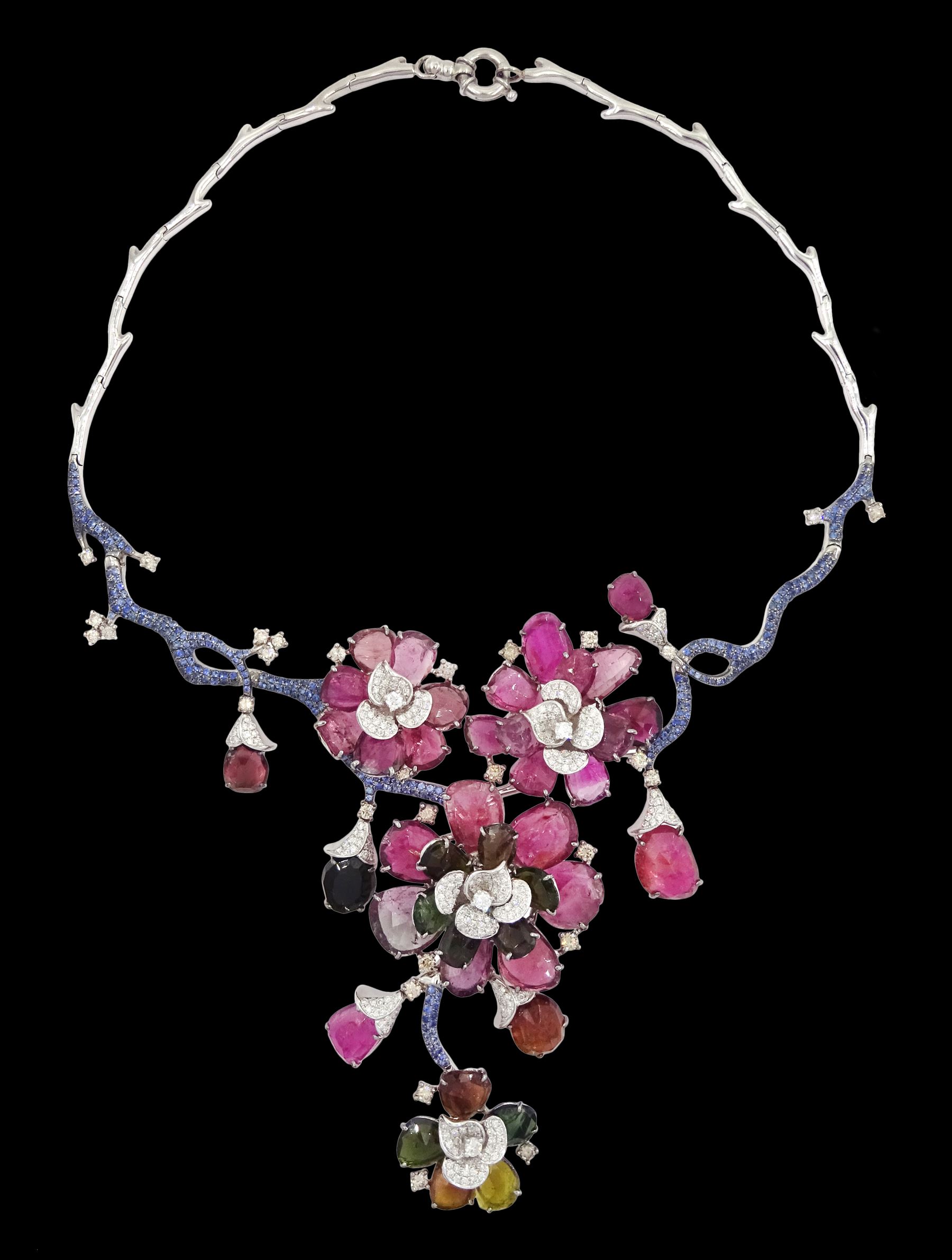 18ct white gold gemstone set floral jewellery suite, comprising necklace, pair of earrings and bracelet, each with tourmaline flower petals, round brilliant cut diamond centres and sapphire stems, stamped