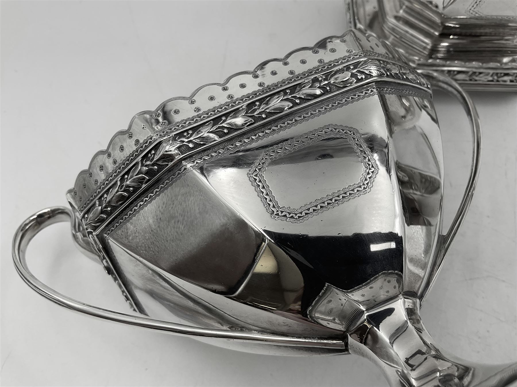 Victorian silver four piece tea service, comprising teapot, teapot stand, twin handled open sucrier and milk jug, each of octagonal form with foliate bud border and engraved decoration including crest to canted panels, and vacant panels, the teapot with ivory finial to the hinged cover and later wooden handle, hallmarked Edward Barnard & Sons Ltd, London1896, teapot including finial H15cm, milk jug including handle H16cm, teapot stand W11.5cm

This item has been registered for sale under Section 10 of the APHA Ivory Act