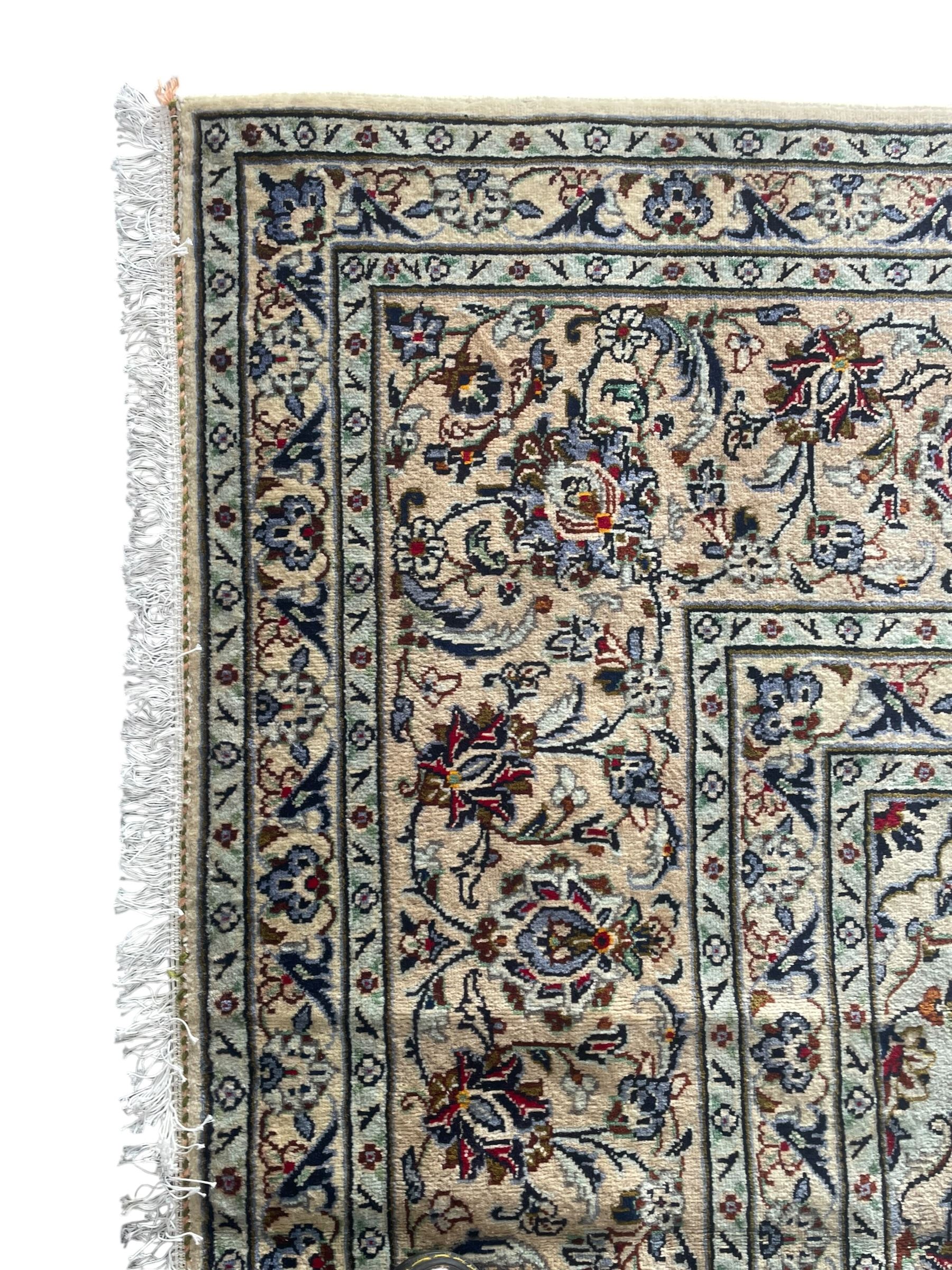 Persian Kashan ivory ground carpet, the field decorated with interlacing foliate branches and stylised plant motifs, scrolling border decorated with repeating palmettes, within floral pattern guard bands