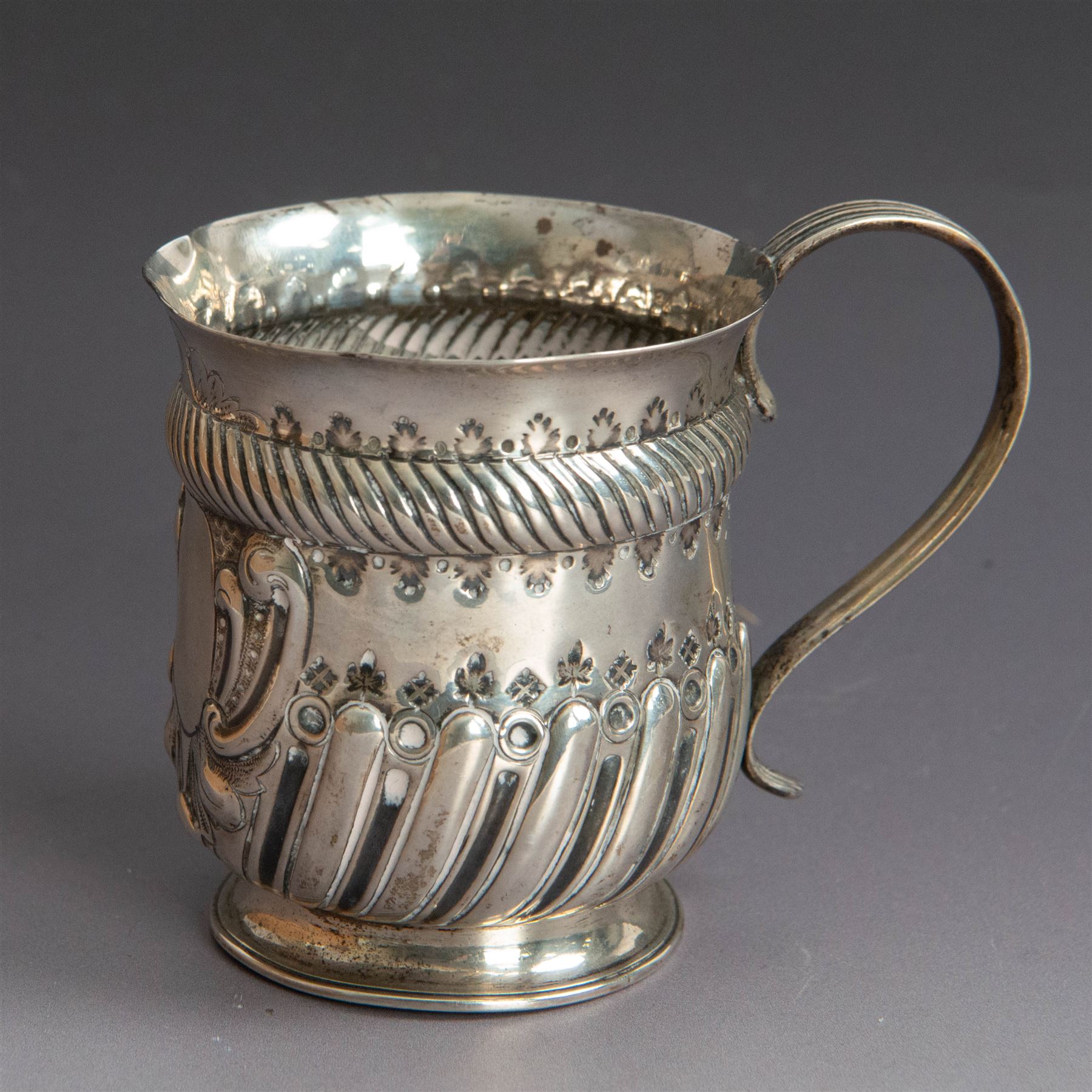 Victorian silver christening mug, of circular form with C scroll handle, embossed with scrolls and foliate decoration, with vacant oval cartouche to body, hallmarked John Aldwinckle & Thomas Slater, London 1890, contained within a tooled leather fitted case, mug H8cm