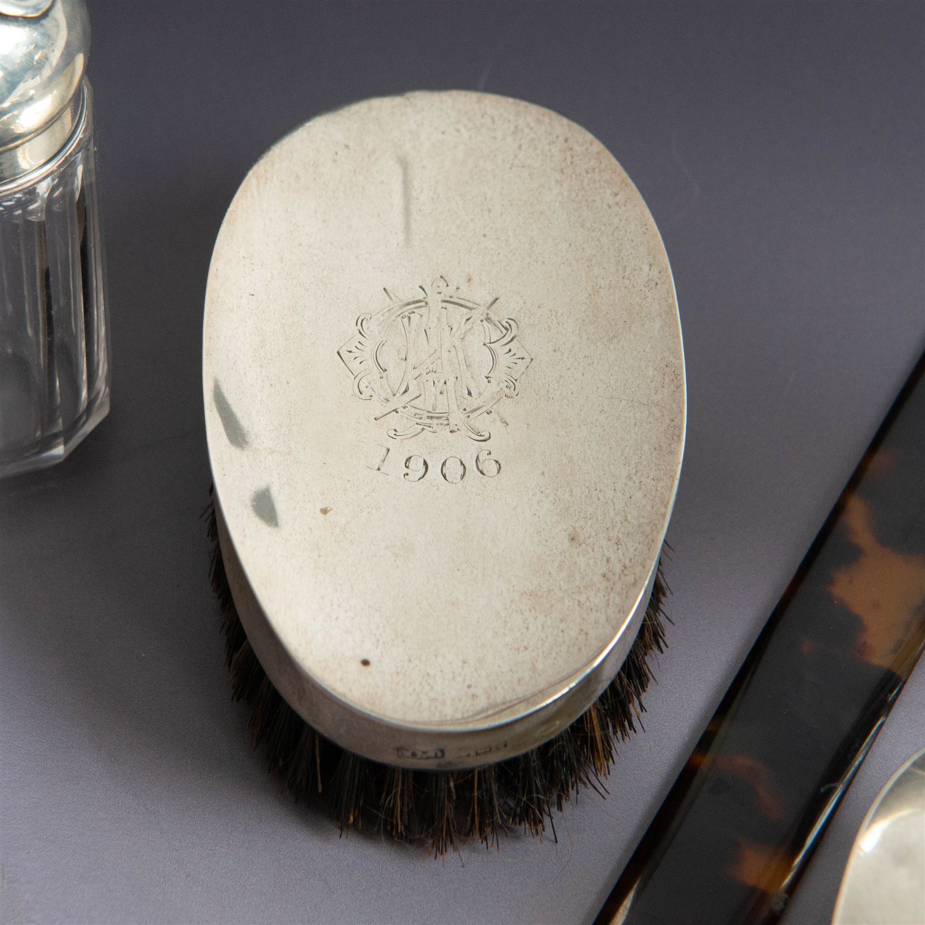 Edwardian tortoiseshell page turner with silver handle, hallmarked Birmingham 1906, maker's mark worn and indistinct, together with a pair of Edwardian silver mounted horsehair brushes engraved with monogram, and two faceted glass jars with silver lids and applied initial N to covers, all hallmarked 