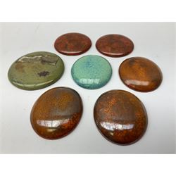 Henry George Murphy (1884-1939), collection of seven Arts & Crafts glazed ceramic roundels, of circular and oval form, five in tones of red and brown and two in tones of blue, turquoise and green in soufflé and high fired finishes, largest example D6.5cm