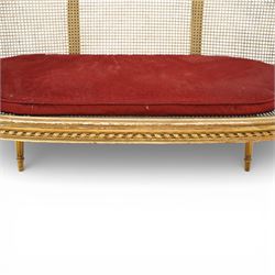 19th century giltwood and gesso settee, with shaped crest rail centred by carved floral detail, the cane back with vertical divisions, upholstered seat with loose cushion, raised on fluted tapering legs