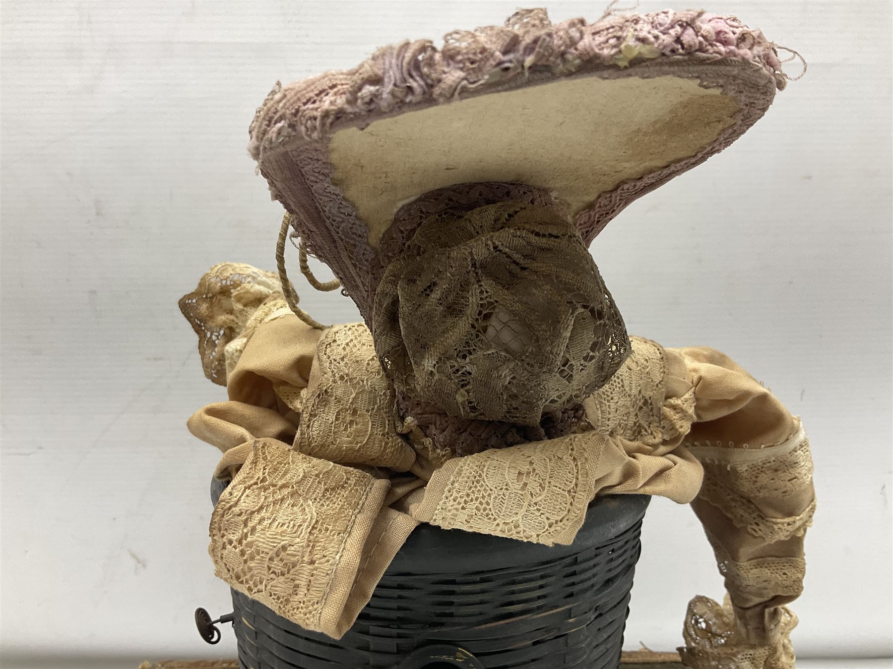 Modern reproduction automaton in the form of a baby doll in a basket clothed in Victorian style lace bloomers and frilled bonnet; clockwork action; on raised platform; with French paper label on base, 29cm wide,