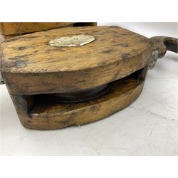 Three ship pulleys comprising wooden block double with swivel eye marked 'wooden block 240mm double rope: 22mm',  wooden block double with upset shackle and wooden block with stiff swivel hook, largest example L50cm