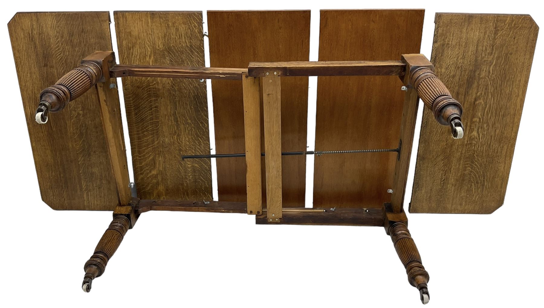 Late Victorian oak telescopic extending dining table, rectangular moulded top with canted corners, three additional leaves, on turned and reeded supports with brass and ceramic castors