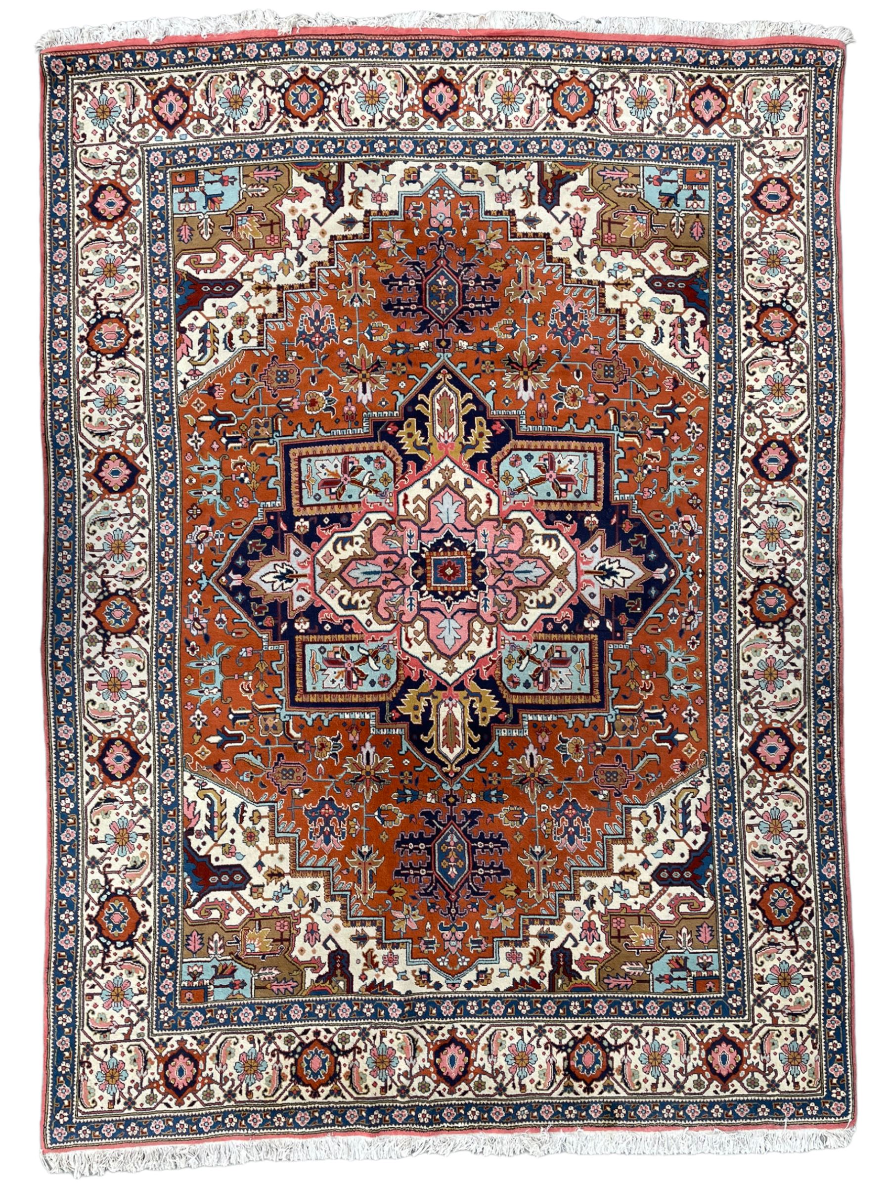 Large Persian carpet, the geometric and stylised floral medallion on rust ground field decorated with stylised plant motifs, guarded ivory border with repeating pattern