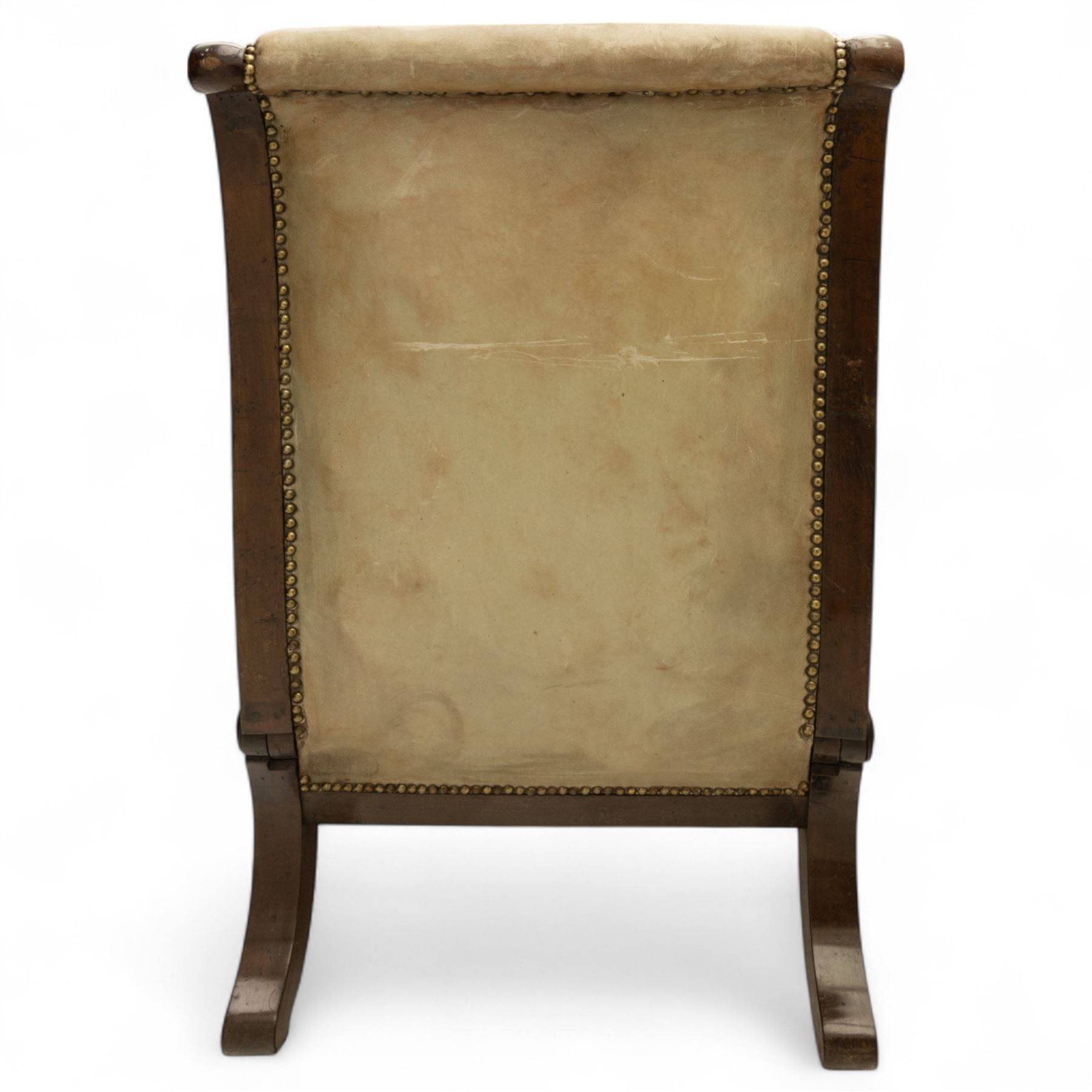 William IV mahogany gentleman's library reclining armchair, leather button upholstered and brass-studded back and seat, above leather-covered arms terminating with carved roundels and foliate scroll-carved ends, underside with brass mechanical trigger reclining lever, the apron with retractable foot rest, supported on lappet carved and turned legs with brass castors, circa 1835