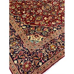 Persian Kashan red ground carpet, central medallion on a field of scrolled foliate, decorated all over with stylised flower and plant motifs, repeating guarded border 