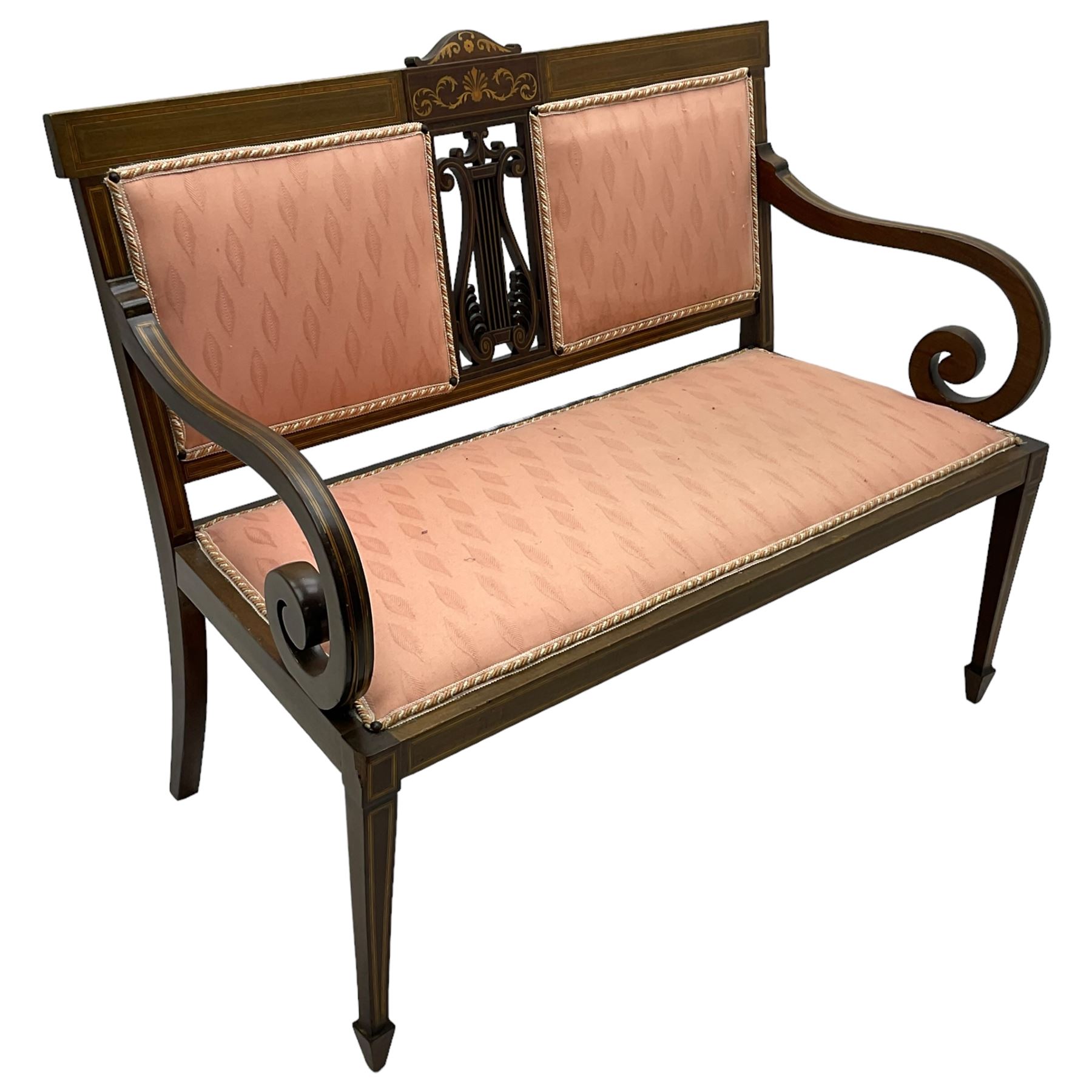 Edwardian inlaid mahogany two-seat settee or hall bench, the cresting rail inlaid with satinwood banding and boxwood stringing, central panel inlaid with scrolled leafy branches over pierced and carved lyre back, upholstered in peach fabric with repeating pattern, scrolled down sweeping arms, on square tapering supports with spade feet 