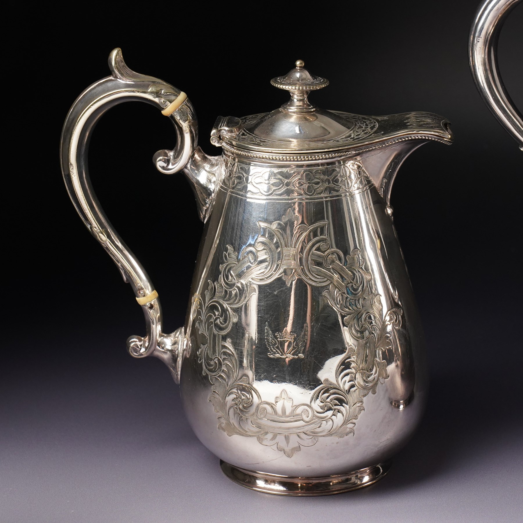 Pair of large silver plated sauce boats with bead edge decoration and C scroll handles engraved with a crest in the form of a winged heart and on shaped supports L20cm Maker probably Hawksworth Eyre & Co and an engraved hot water jug and a matching smaller jug with the same crest and by the same maker