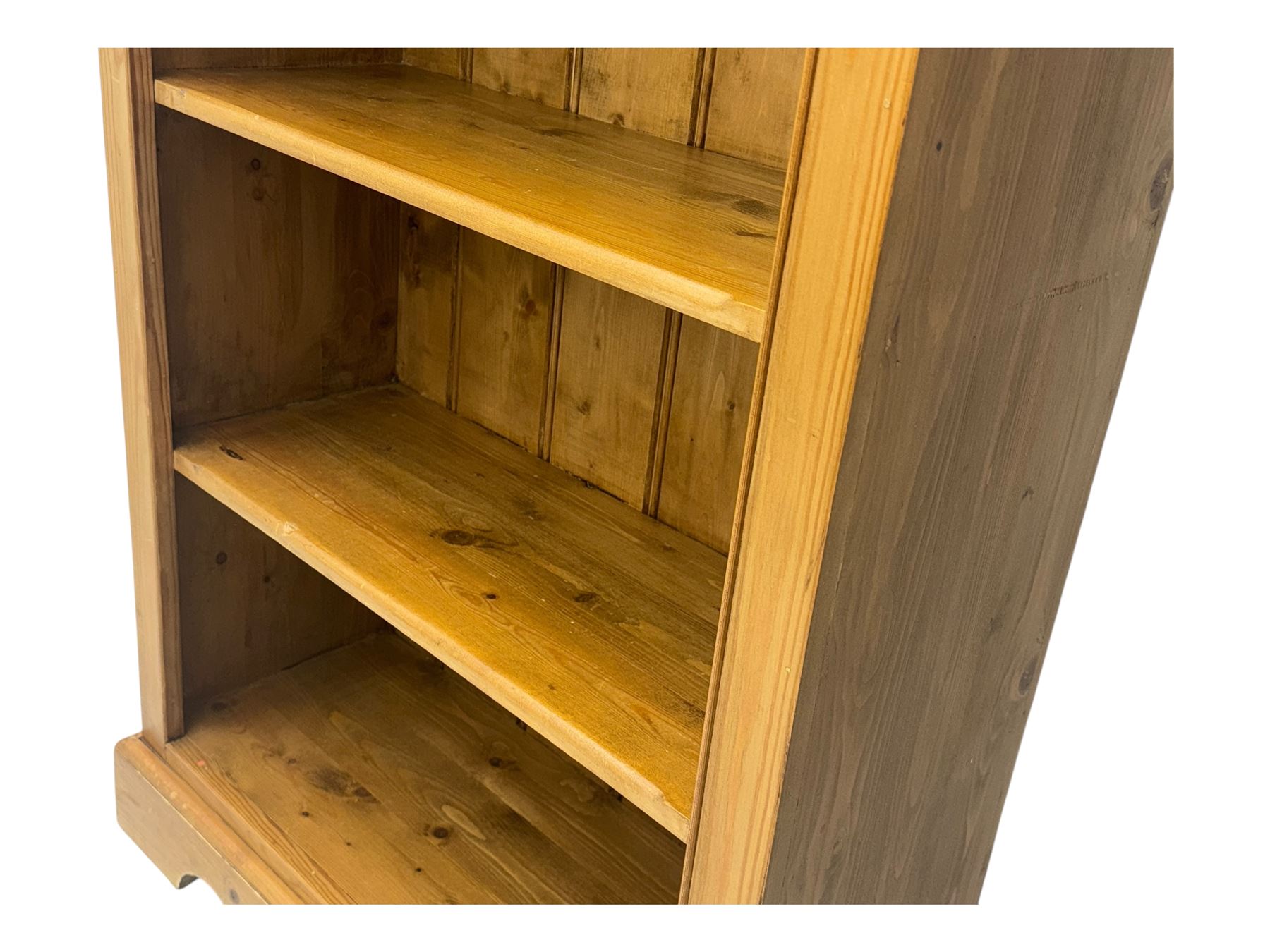 Early 20th century pine bookcase, projecting cornice over arched open shelving area with five adjustable shelves, on shaped plinth base