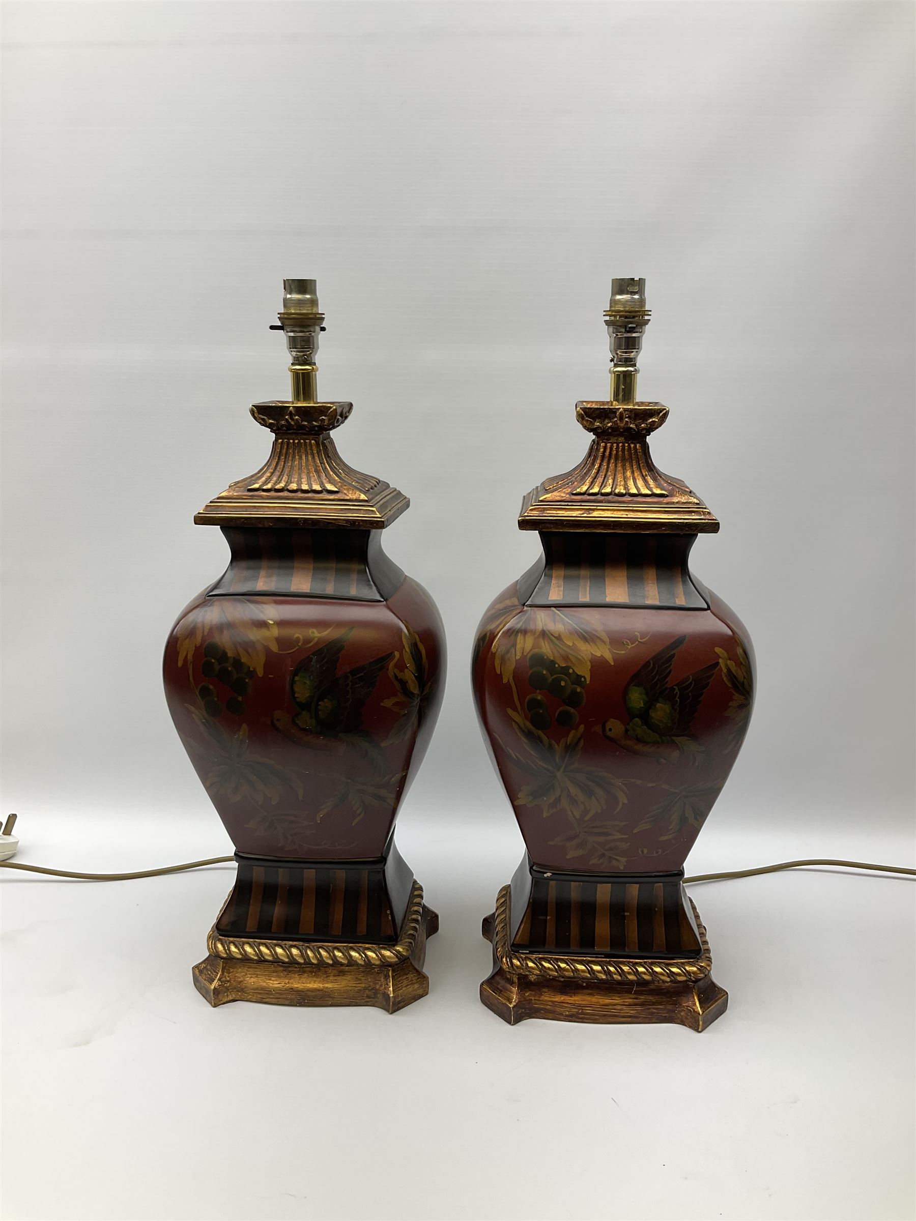 Pair Oriental table lamps decorated with birds in a tree with fruit, on a red ground with a gilded base together with cream lampshades H57cm, without lampshade. 