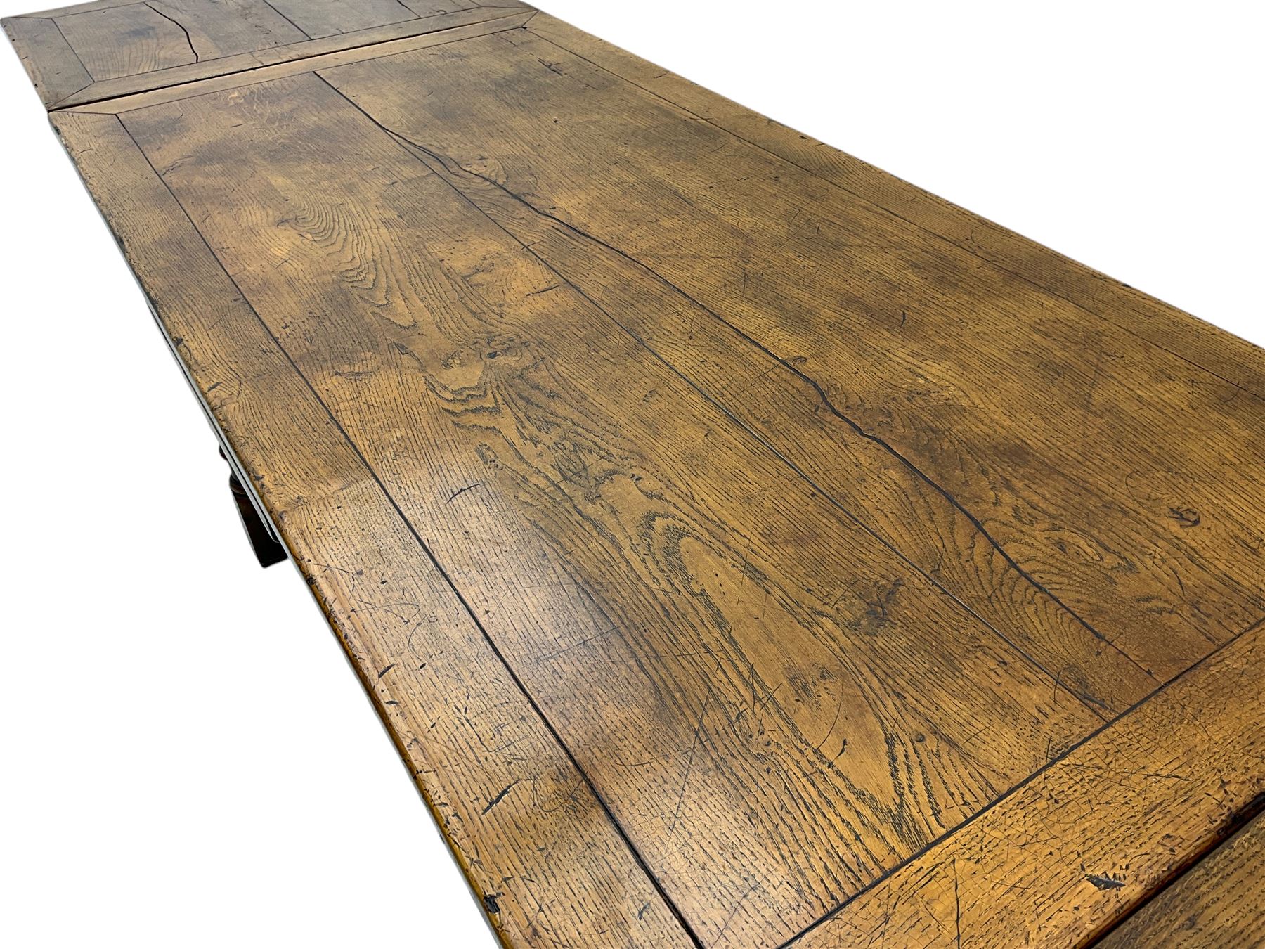 Early 20th century Jacobean design draw-leaf oak dining table, rectangular top with carved frieze depicting scrolling foliage and grape clusters, sliding extending leaves, raised on robust turned supports united by H-stretcher  