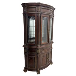  Kevin Charles American walnut demi lune display cabinet with illuminated interior, projecting cornice, two bevel edge glazed doors enclosing two adjustable shelves above single drawer and four cupboard doors with wine rack, carved scrolling supports