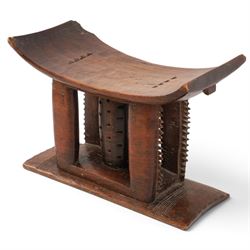 African carved hardwood headrest, having flared edges, raised on a stepped plinth base with further carved detailing, H34cm