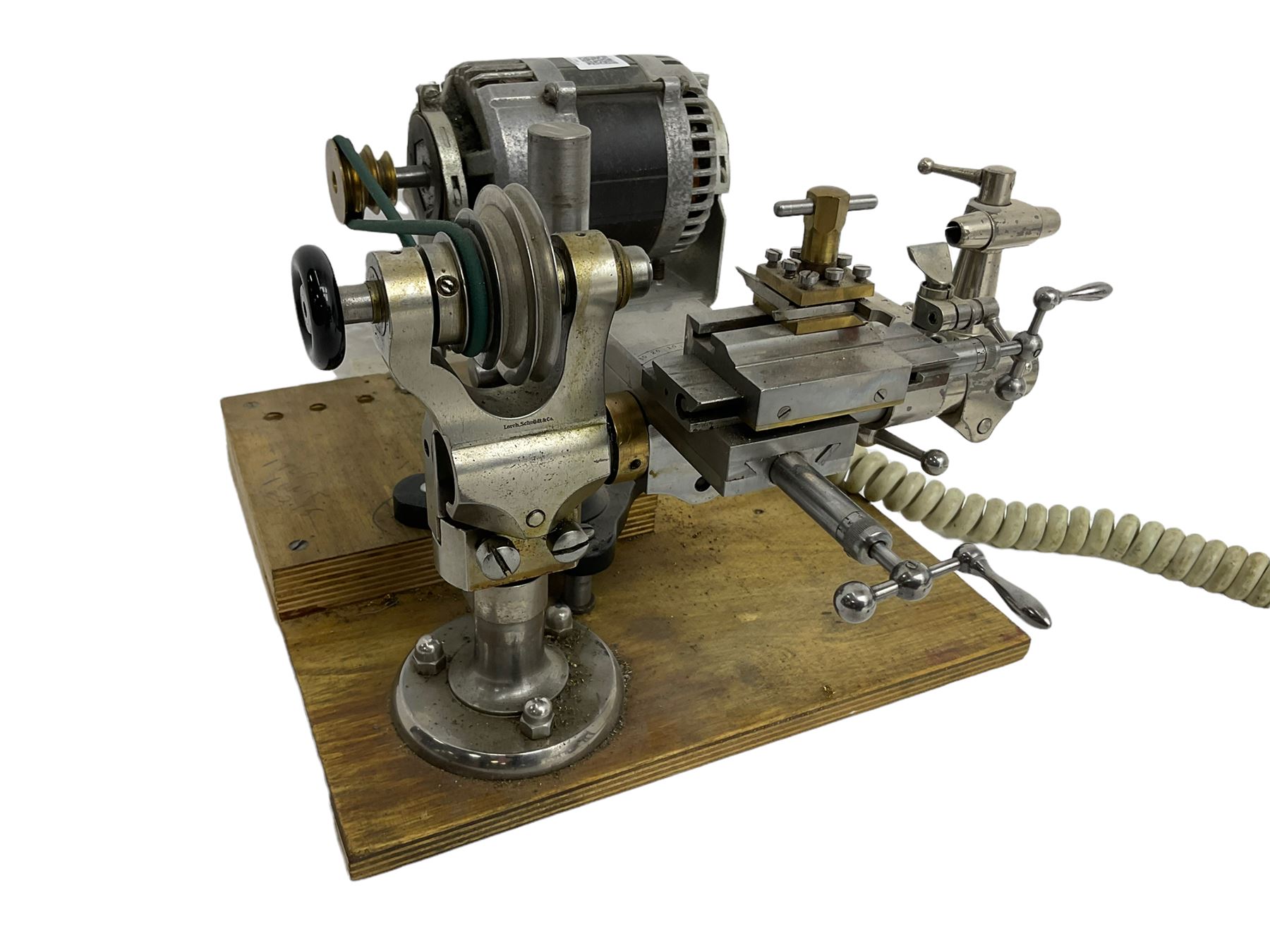 Lorch 6mm watchmakers lathe with tailstock, crosslide, tool rest, four-way tool post, pulleys and motor. Mounted on a wooden board.
