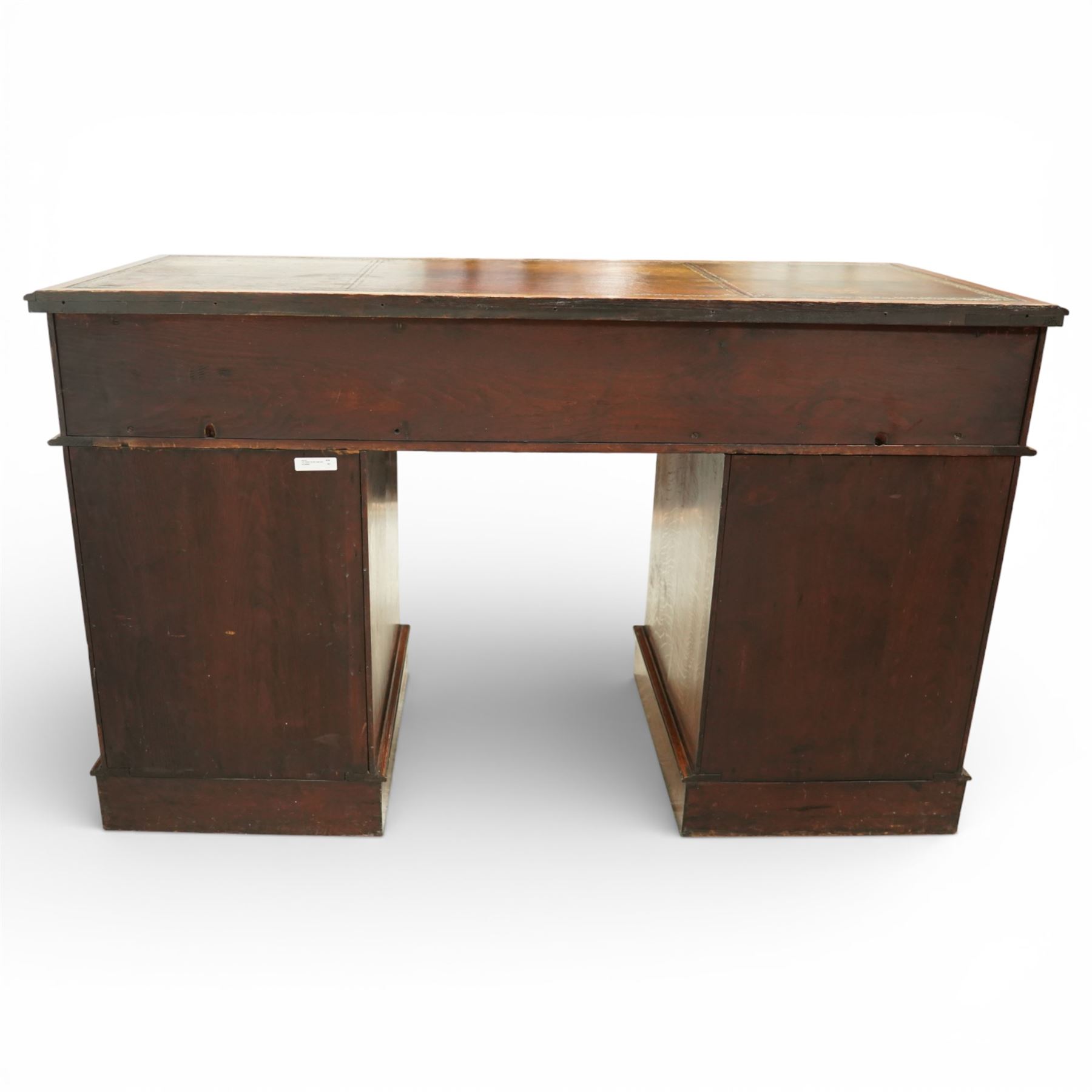 Late Victorian oak nine drawer desk, the rectangular top inset with a tooled leather writing surface bordered in gilt, above three frieze drawers and two pedestal cupboards each fitted with three graduated drawers, all with brass swan neck handles, raised on plinth bases