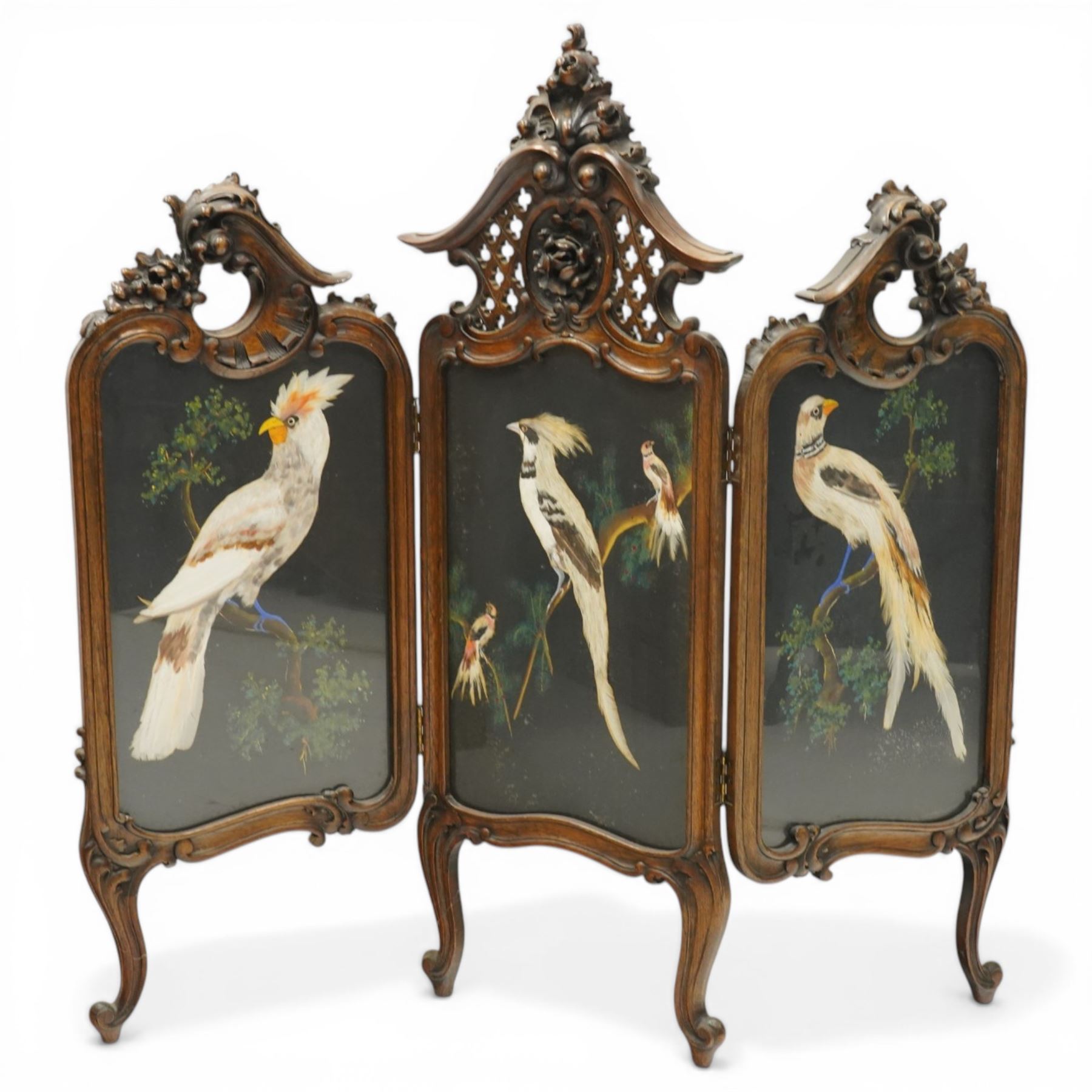 Rococo Revival carved hardwood framed triple panel fire screen, pierced and carved foliate and cartouche pediments with C-scrolls and scallop decoration, over three glazed panels depicting exotic birds of Mexican feather art, on cabriole supports with scroll feet