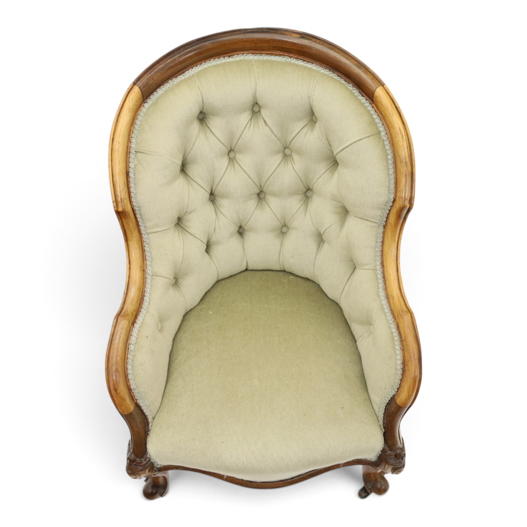 Victorian carved walnut framed armchair with matching stool, the tub-shaped chair with moulded and shaped frame and arm terminals, raised on scrolled cartouche carved supports with scroll feet and castors, buttoned back and sprung seat upholstered in sage green fabric; the small circular footstool with buttoned seat and scroll supports (W36cm H15cm)
