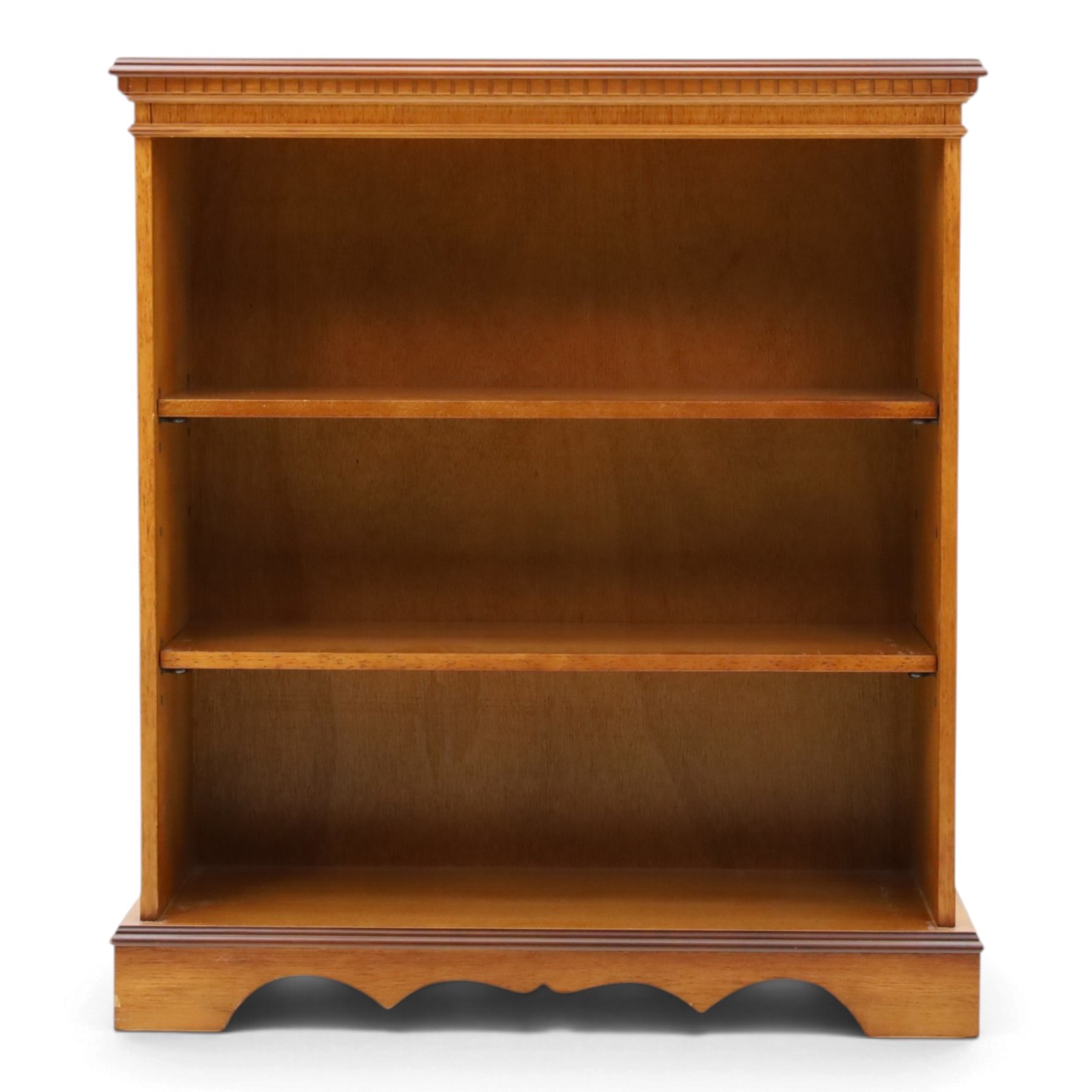 Contemporary mahogany and yew wood open bookcase, dentil cornice above two adjustable shelves, shaped apron and bracket feet 
