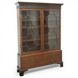 Early 20th century mahogany glazed bookcase, the moulded cornice above a carved frieze with interlaced ornament, enclosed by a pair of astragal glazed doors with geometric glazing bars, the base fitted with two short over two long drawers with brass swan neck handles, raised on bracket feet