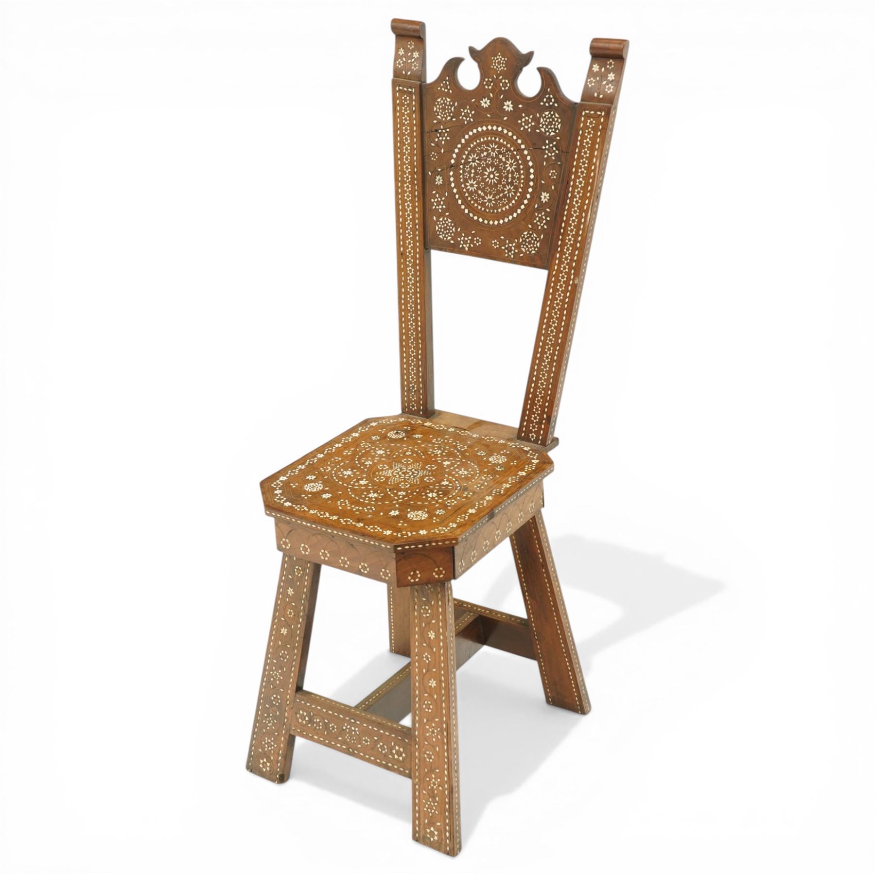 19th century Syrian olive wood and ivory inlaid chair, the shaped back and cresting above a panel centred by a circular starburst roundel within geometric and foliate marquetry and stringing, the tapering uprights and frame extensively inlaid with repeating ivory motifs, the octagonal seat similarly decorated, raised on splayed legs united by H-stretcher with further inlaid ornament