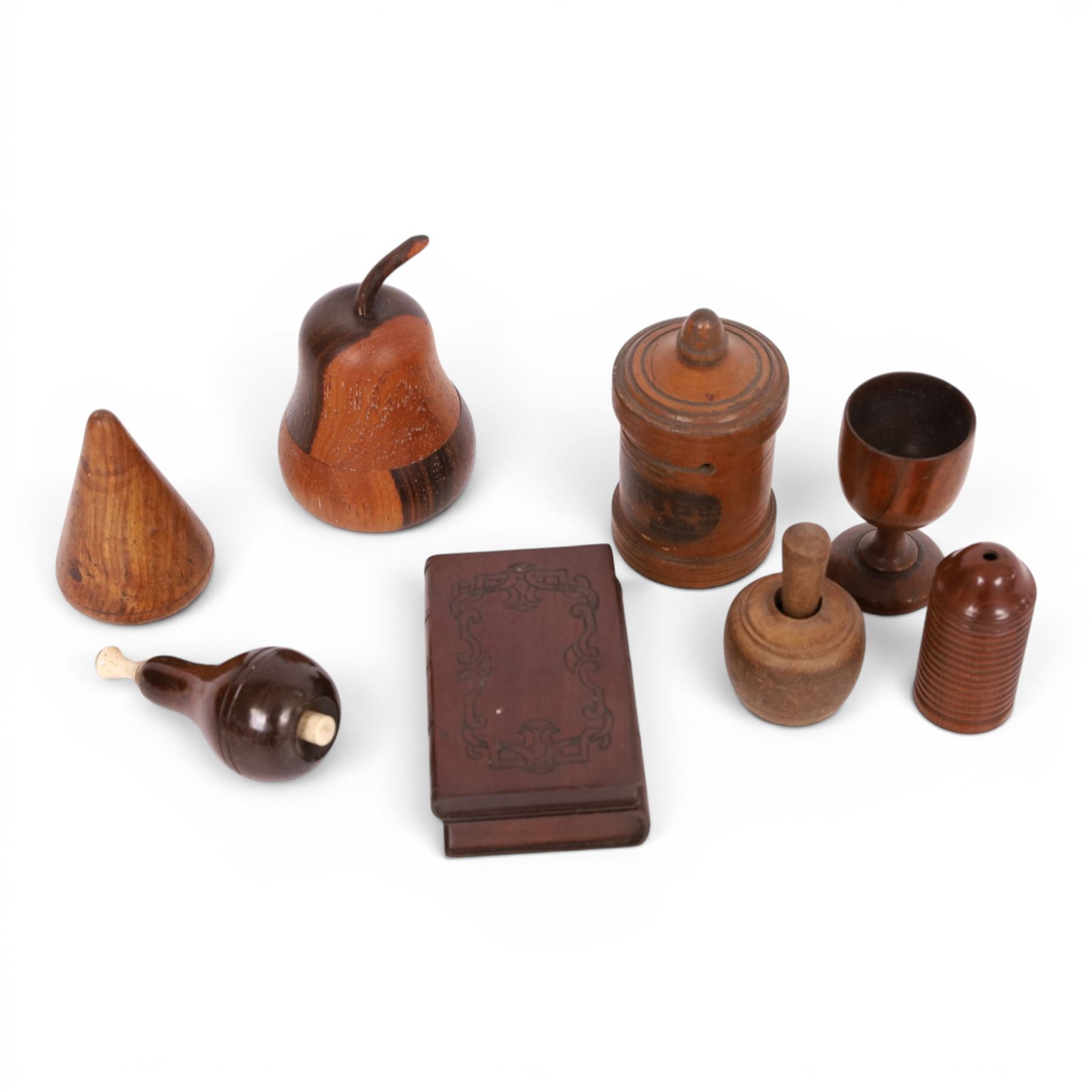 Group of treen, comprising, Mauchline ware coin box, box modelled as pear, egg cup, butter stamp, bell push, sewing implement, weaving tool, and box modelled as book