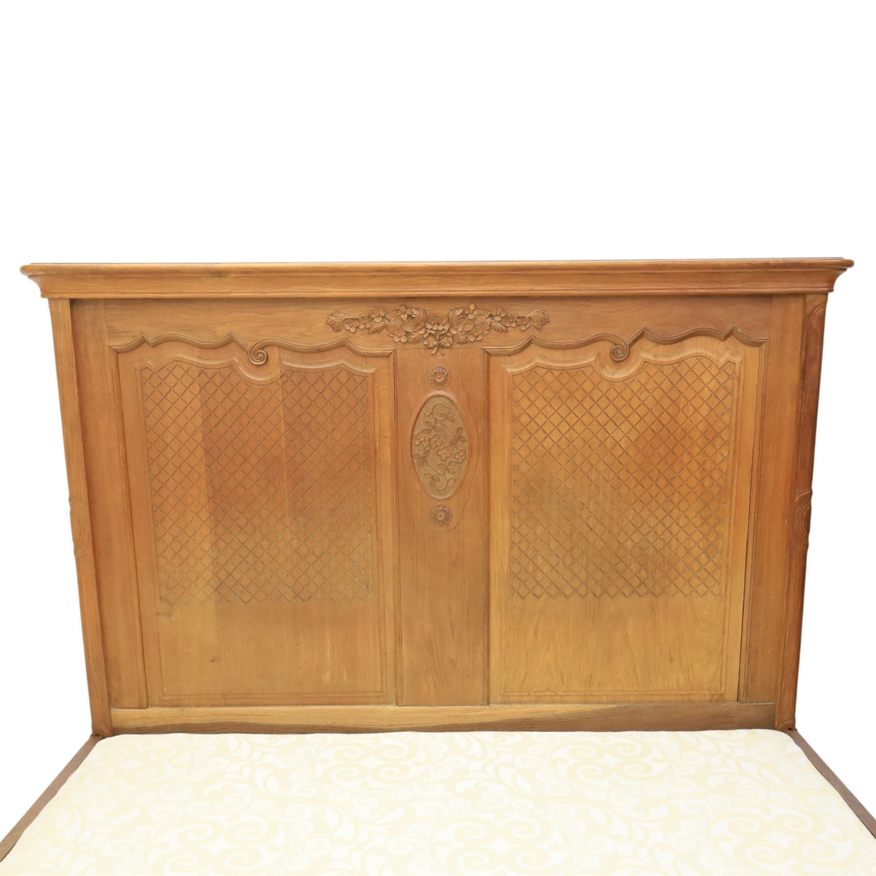 Early 20th century French oak double bedstead, the shaped and moulded headboard carved with central floral cartouche and scrolling foliage above lattice carved panels, the conforming footboard with pierced and carved decoration, shaped apron with foliate carving, raised upon cabriole supports