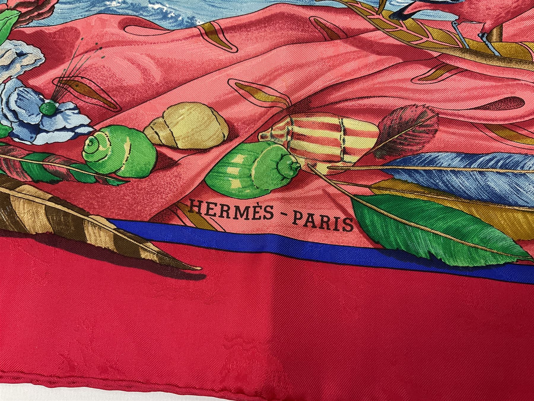 Hermès 'Christophe Colomb Découvre l'Amérique' jacquard silk scarf, designed by Carl de Parcevaux in 1992, limited edition for the bi-centenary of the discovery of America, printed with a central image of Christopher Columbus' ship at sea, surrounded with colourful stylised feathers, birds, flags, globes, shells and flowers, contained within vibrant red border, with rolled hand stitched edges and Hermes material label, 87cm square