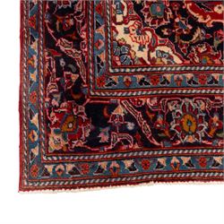 Two Persian rugs, the larger with a crimson field decorated with three linked indigo medallions amongst flowering tendrils, shaped floral spandrels and an indigo palmette border, (161cm x 129cm), the smaller with a crimson field centred by an ivory rosette amongst stylised flowering plants, within a dark floral border, (114cm x 79cm) (2)