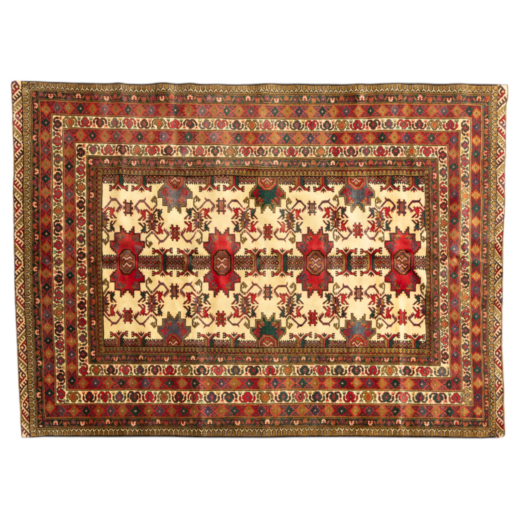 North East Persian Gochan hand-knotted rug, ivory field decorated with a vertical column of stepped polygonal medallions flanked by stylized geometric floral motifs enclosed by multiple borders incorporating rosette and reciprocal devices, in a palette of madder red, indigo, olive green, and aubergine, with cotton fringe ends  