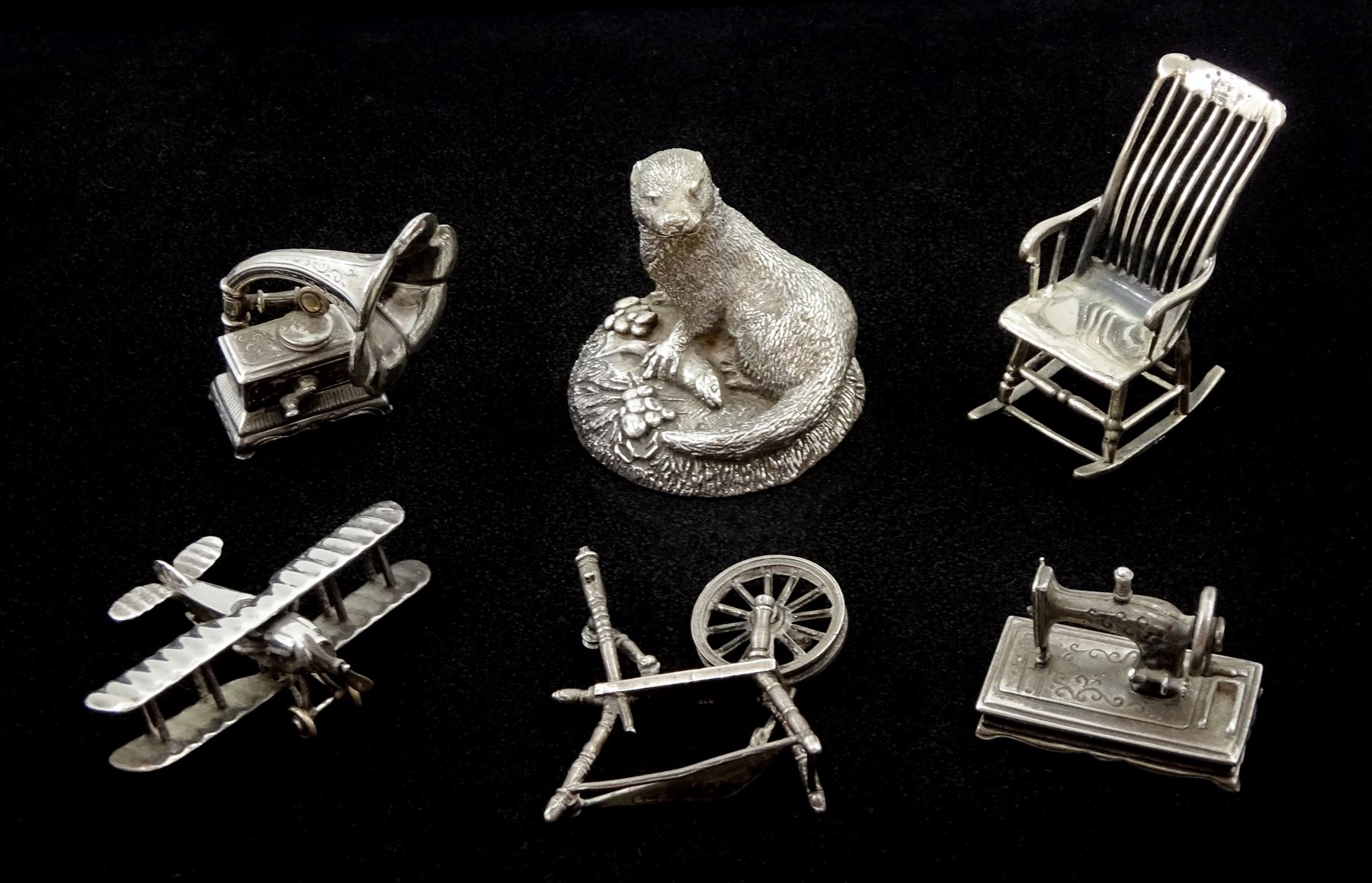 Collection of silver miniatures including a WWI fighter aeroplane the underside of the body engraved 'Bristol' by Italian Medusa Oro 925, gramophone, spinning wheel by S M C, London import marks 1982, sewing machine and chair, all stamped 925 or hallmarked and a silver filled otter by Country Artists