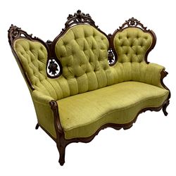 Victorian walnut settee, triple back with pierced and scroll-carved cresting rails over carved fruit and foliage decoration, upholstered in buttoned green fabric, serpentine seat and carved apron, on cabriole feet