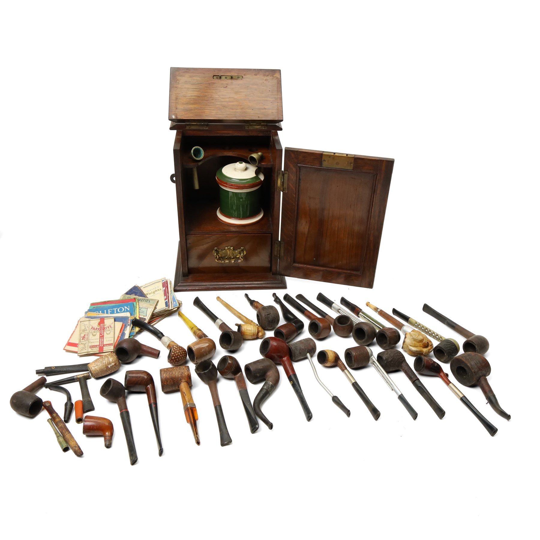 Edwardian oak smokers cabinet with carved panel door and hinged lid and a collection of various pipes and other items