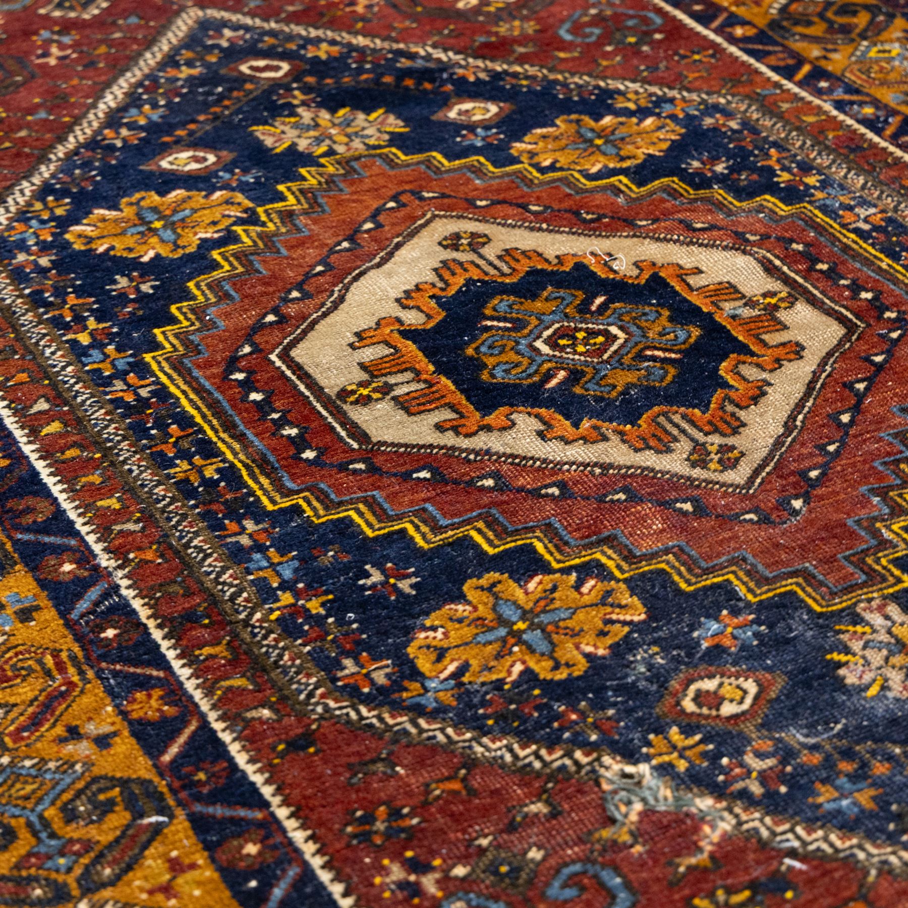 Turkish Anatolian wool rug, central stepped medallion on dark blue lozenge field, red spandrels with stylised hooked motifs, ochre border decorated with repeating geometric motifs and guard stripes