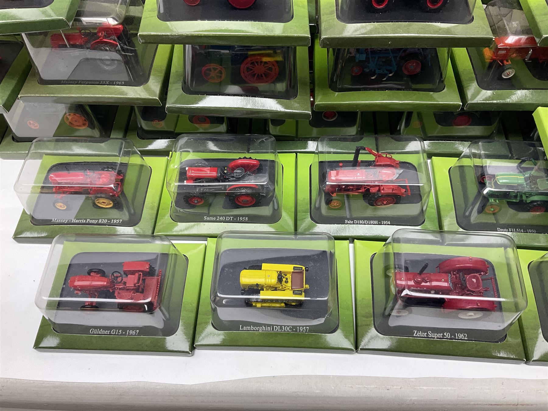 Eighteen issues of Tractors and The World of Farming magazine, together with sixty diecast tractors, all in original packaging, in three boxes 