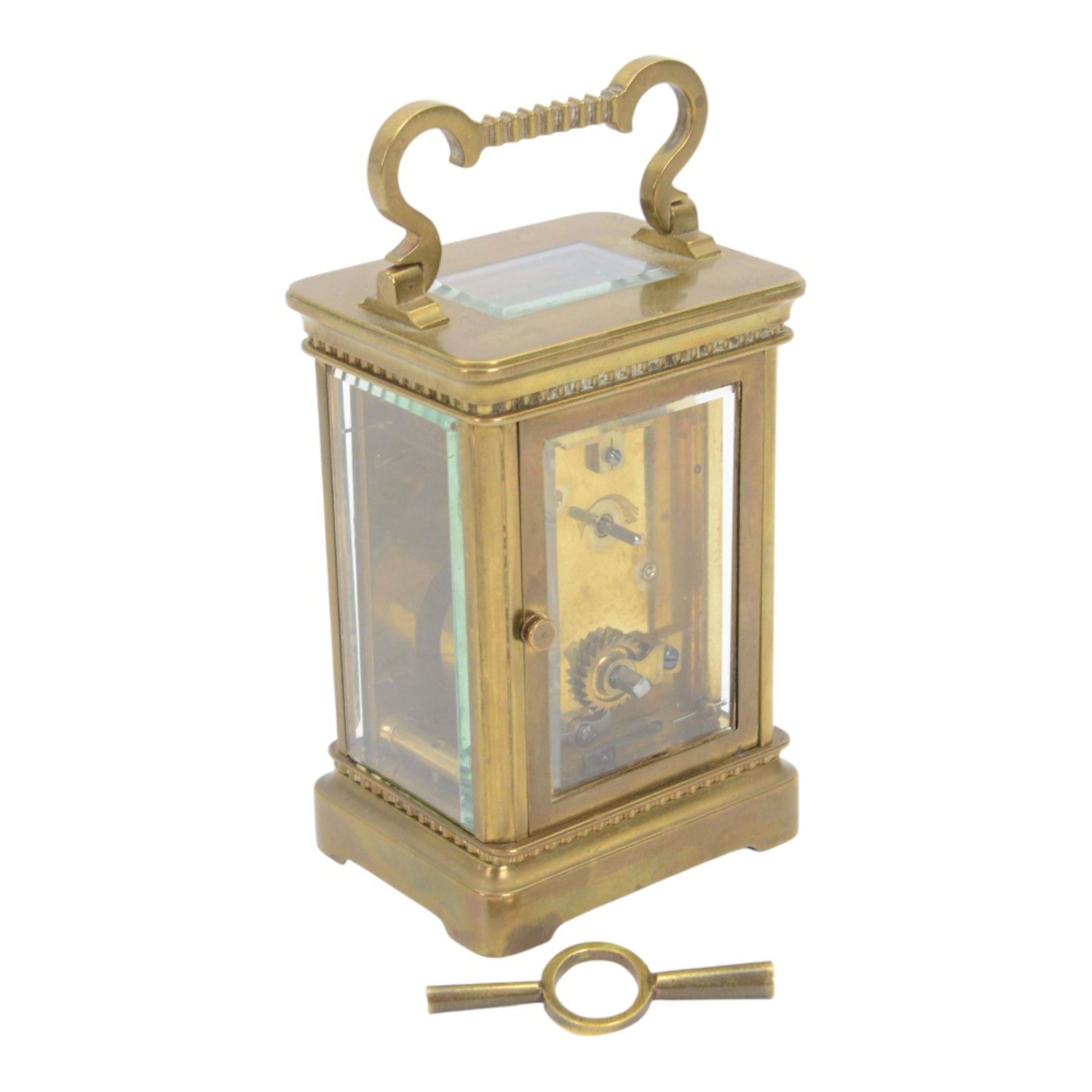 French-Edwardian 8-day timepiece carriage clock with a cylinder platform escapement, anglaise style brass case with four glass panels, dial with a polished gilt mask and foliate decoration, white enamel chapter with Arabic numerals and steel spade hands, . With Key. 