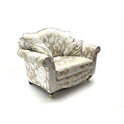 Snuggler armchair upholstered in a pale gold ground fabric with floral pattern, shaped cresting rail, scrolling arms